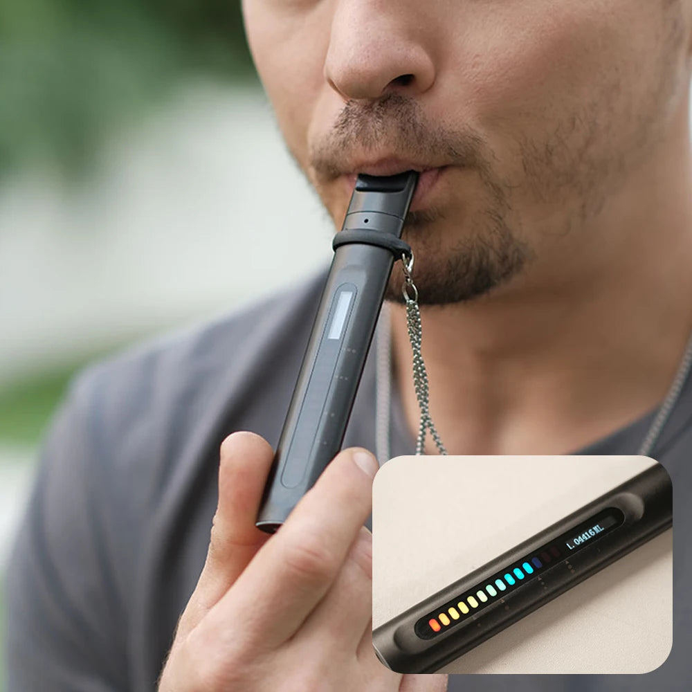 Man using a slim, black, handheld respiratory training device with a glowing LED progress display and a lanyard.