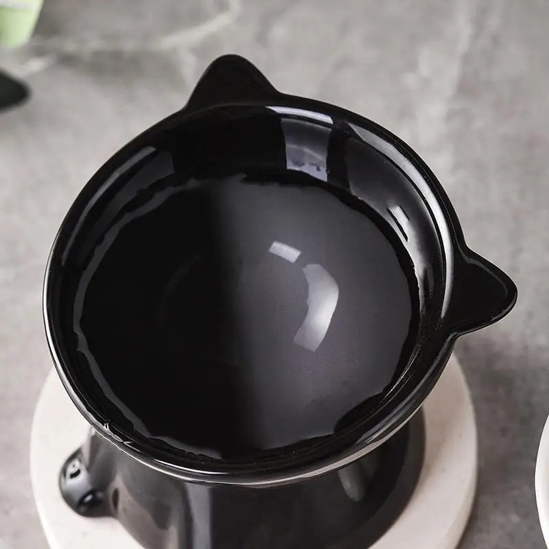Glossy black, cat-ear shaped elevated pet bowl on a white base, designed with a 15-degree tilt for neck comfort.