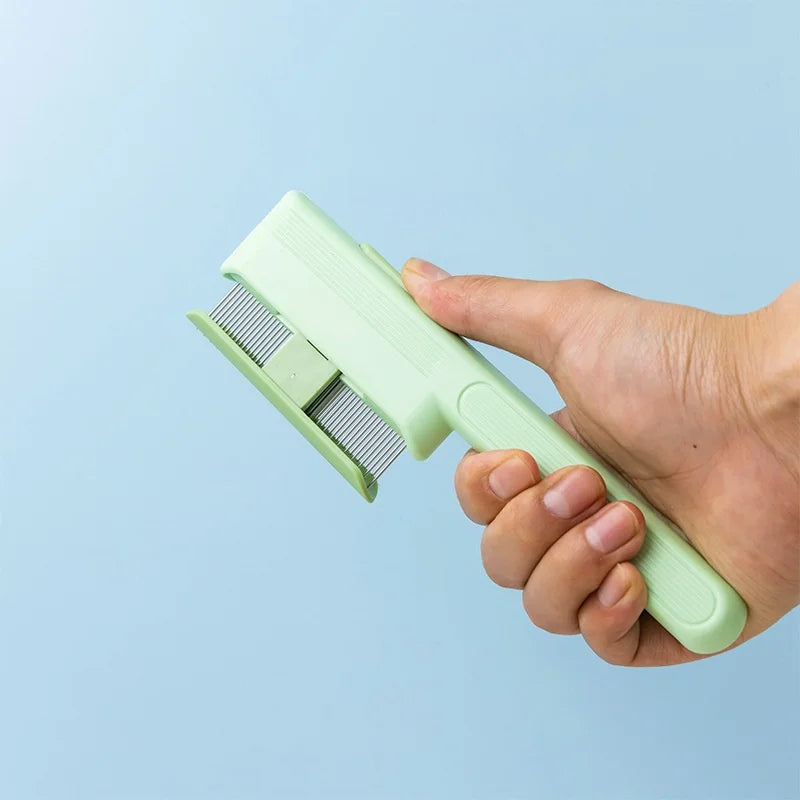 Hand holding a light green pet grooming comb with fine metal teeth against a light blue background.