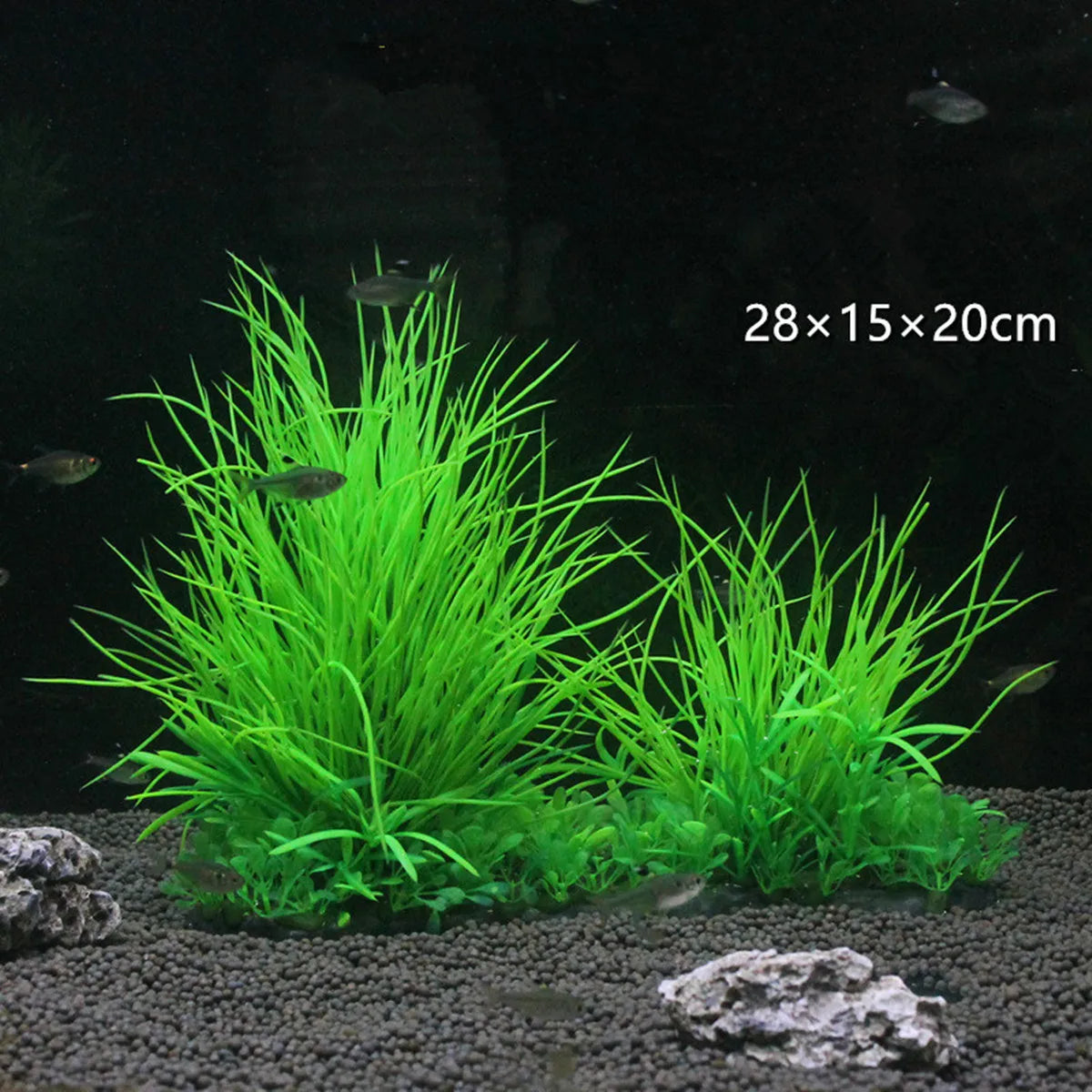 Two vibrant, neon-green artificial aquarium grass plants in a dark fish tank with gravel and small fish.