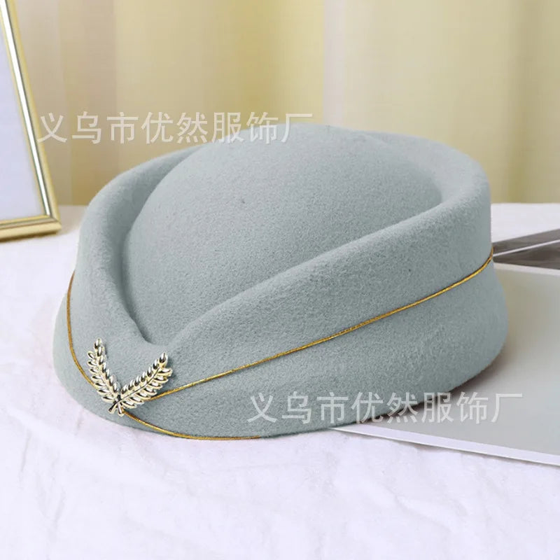 Vintage-style pale blue felt pillbox hat featuring gold trim and a silver laurel leaf emblem.