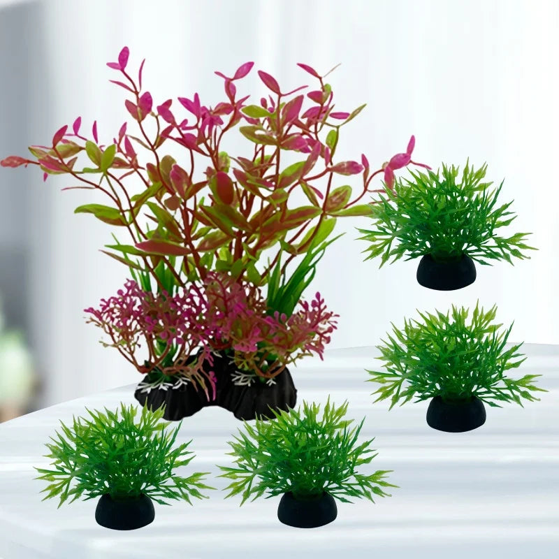 A set of five artificial aquarium plants, featuring one large pink and green plant and four small, bushy green shrubs.
