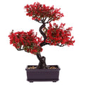 Artificial bonsai tree with vibrant red leaves and a dark twisted trunk in a rectangular dark pot with pebble soil.