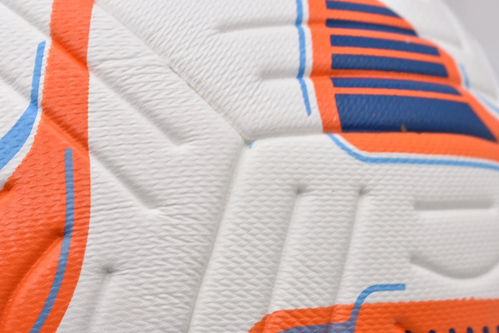 Close-up of a white textured football with orange and blue geometric patterned panels and debossed detailing.