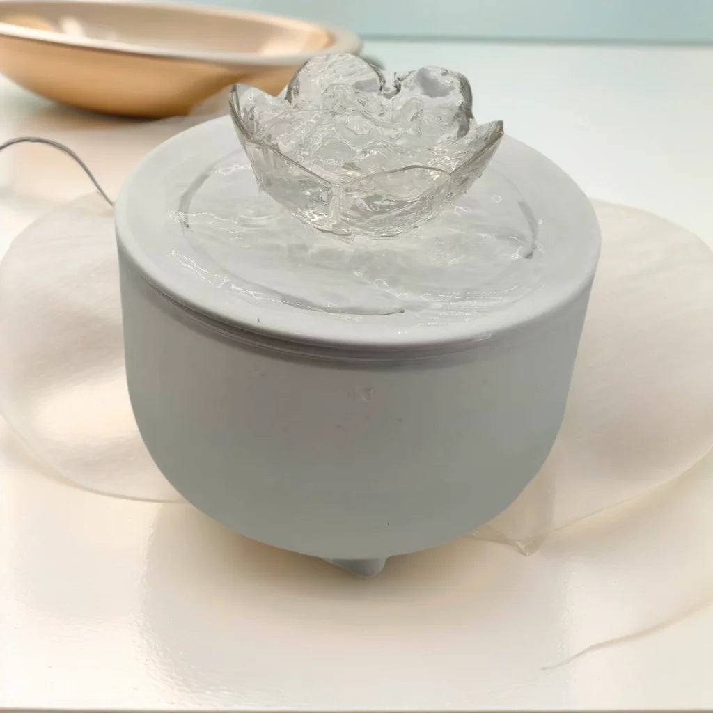 White circular pet water fountain with a clear, flower-shaped plastic top piece.