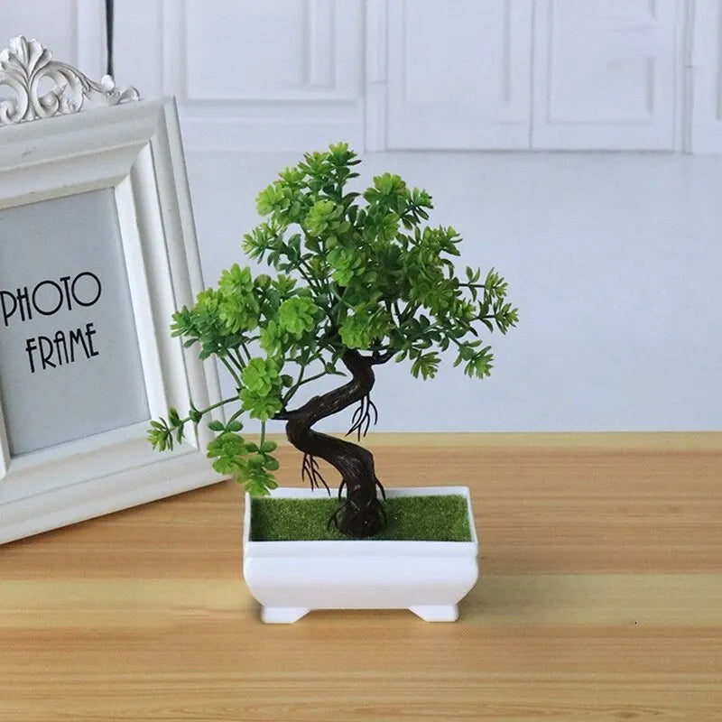 Artificial bonsai tree with green plastic leaves and a curved brown trunk in a small white rectangular pot.