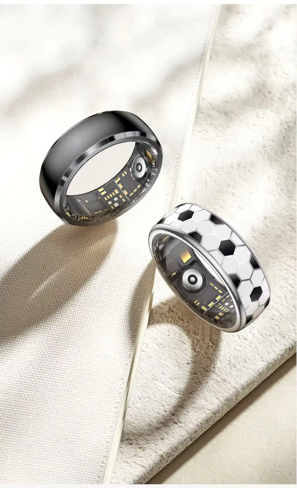 Two smart fitness rings: one matte black, one with a white and black football pattern, showing interior sensor details.