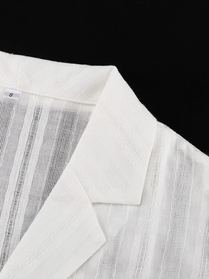 Close-up of a white, sheer collared shirt featuring a textured, vertical striped pattern.