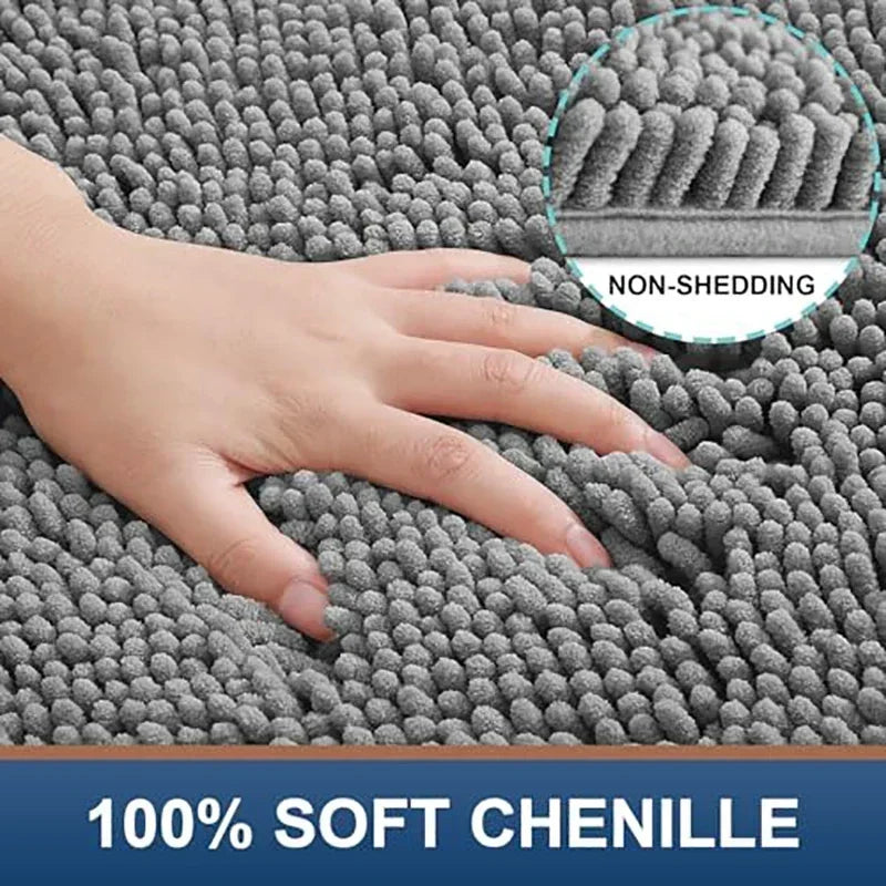 Hand touching a soft, grey, non-shedding chenille dog doormat with a thick, absorbent textured surface.