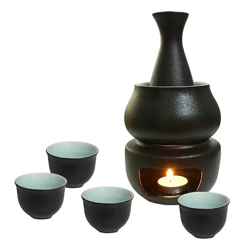 Black ceramic sake set with narrow-necked bottle, warmer cup, lit candle stove, and four small cups with light blue interiors.