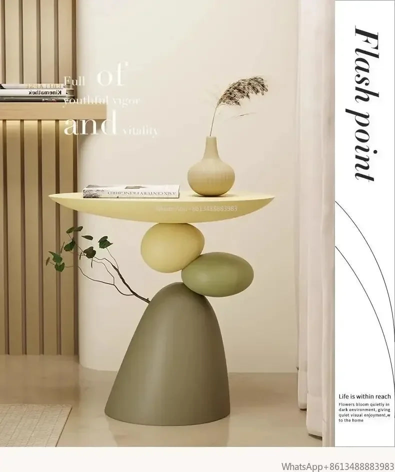 Minimalist cream-coloured side table with a sculptural, stacked stone-effect base in muted green and yellow tones.