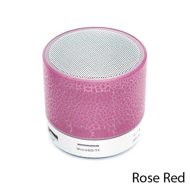 Small rose red portable Bluetooth speaker with a crackle-effect LED light finish and a white circular base.