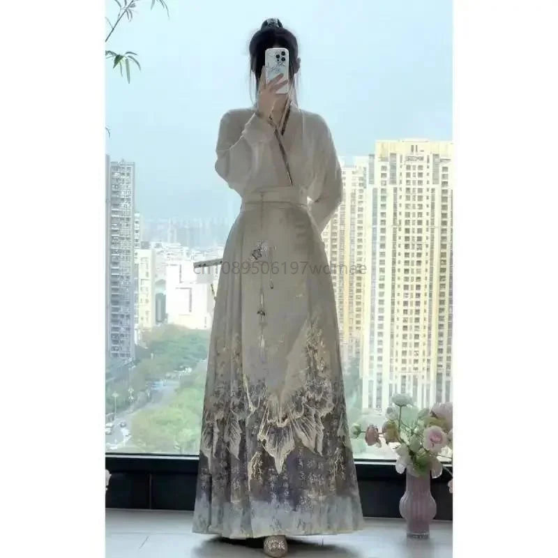 Elegant beige Hanfu-style maxi dress with long sleeves, waist tie, and flowing skirt featuring ornate grey floral hem.