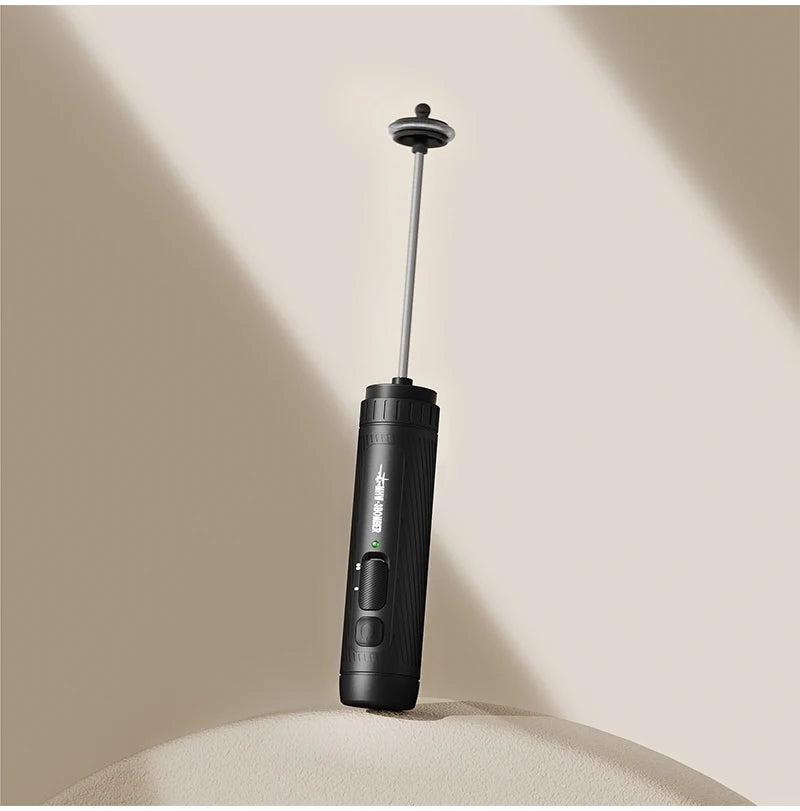 A matte black handheld milk frother with a sleek, minimalist design and a long silver metal whisk attachment.