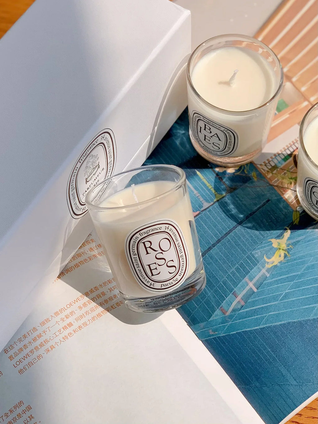 Two scented candles in glass jars with cream wax and minimalist circular labels, presented with a white gift box.
