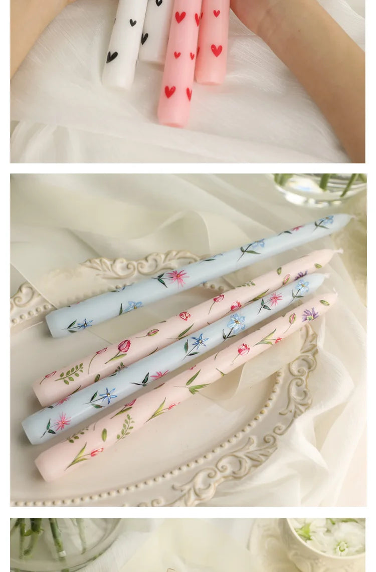 Set of pastel tapered dinner candles featuring delicate heart and floral patterns on white, pink, and blue wax.