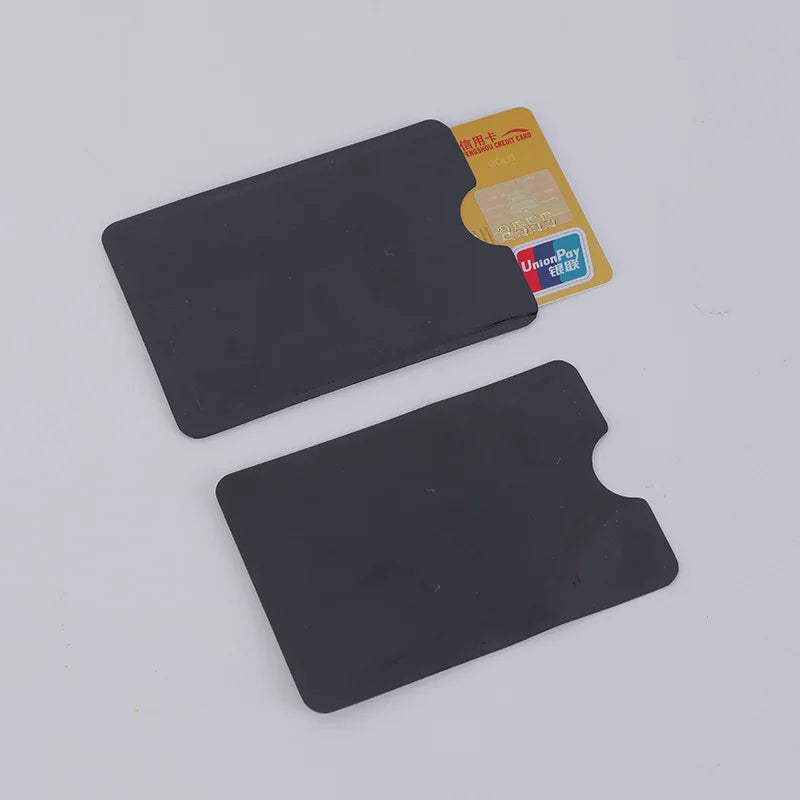 Two matte black plastic card sleeves with thumb notches, one shown containing a gold-colored credit card.