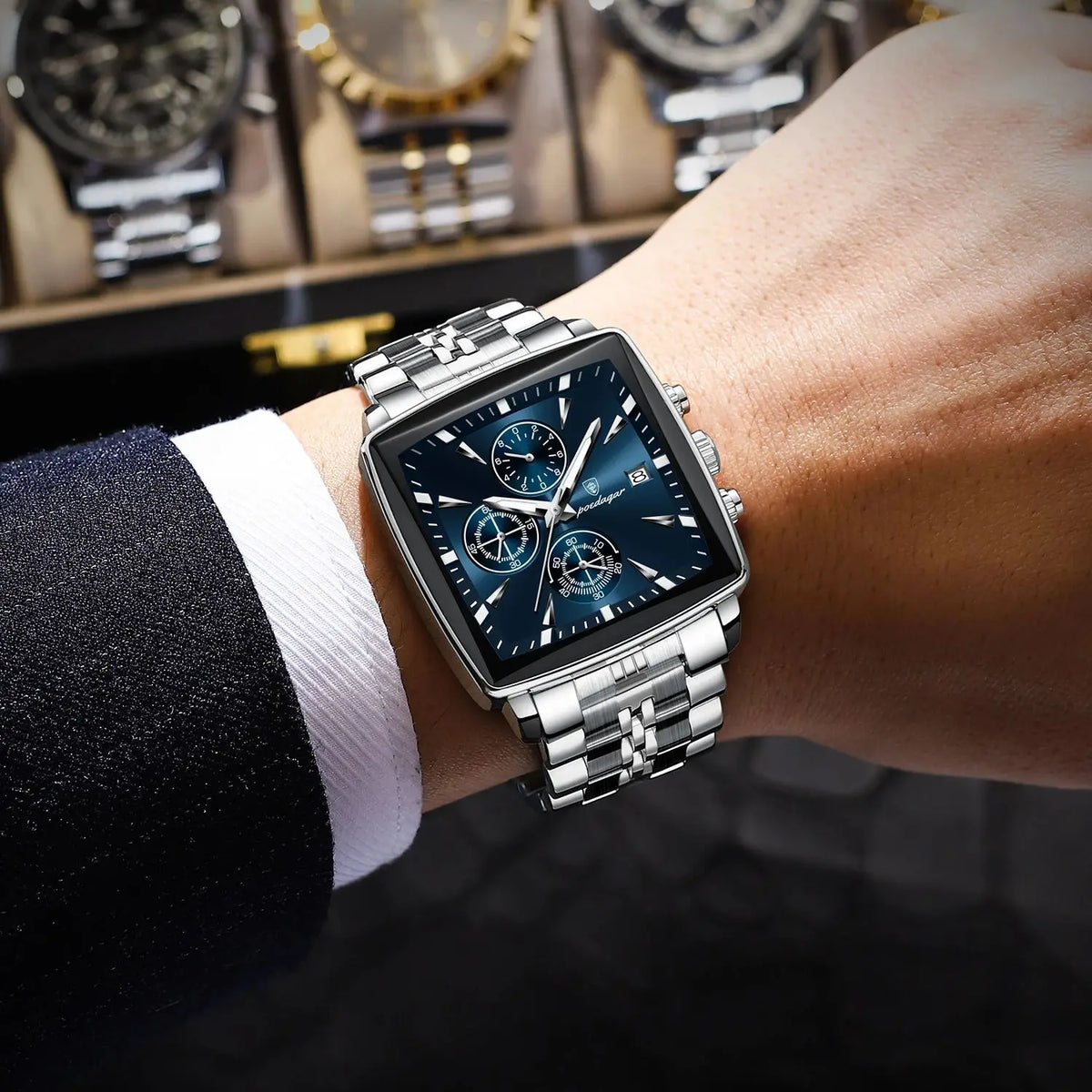 POEDAGAR silver square men's watch with blue dial, chronograph subdials, and stainless steel link bracelet.