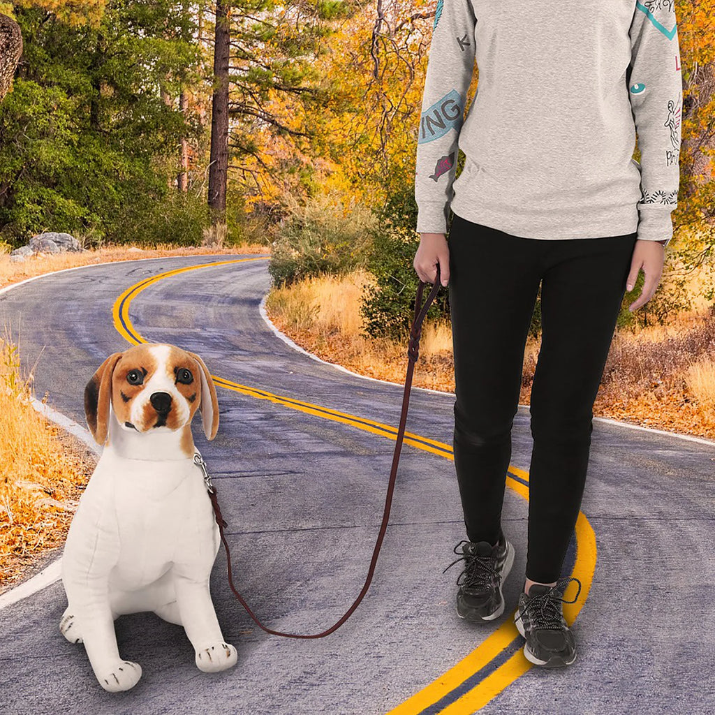 A person walking a beagle on a slim, dark brown leather dog lead against a woodland road backdrop.