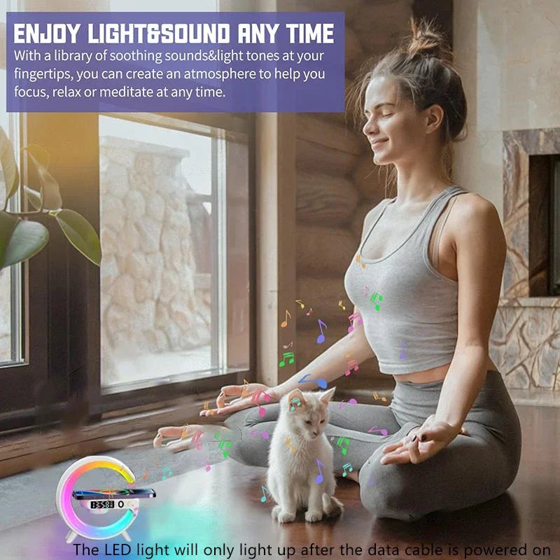 A white, circular Bluetooth speaker with vibrant RGB lighting and a built-in wireless phone charging pad.