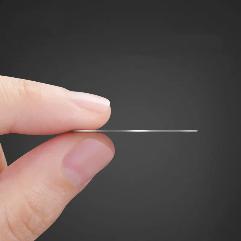 Fingers holding a thin, minimalist silver circular disc against a dark grey background.