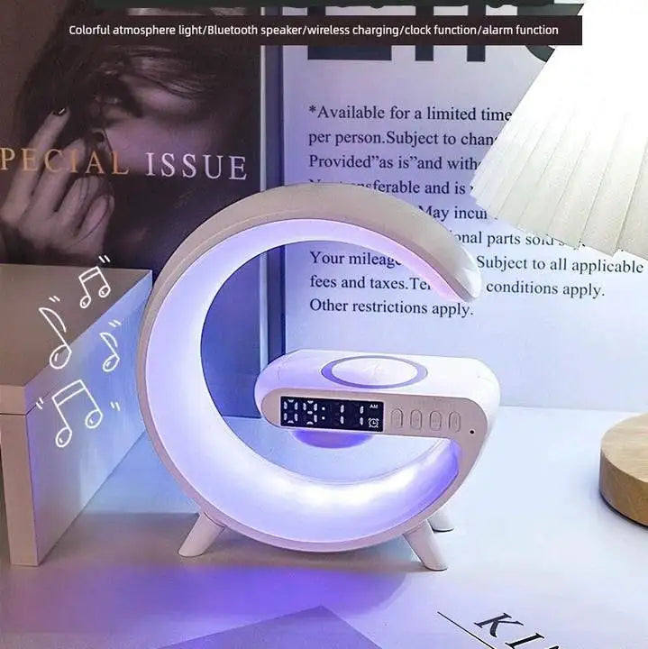 White G-shaped Bluetooth speaker with an integrated digital clock, RGB night light, and a wireless charging pad.