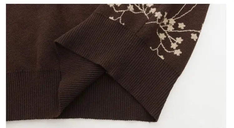 Close-up of a brown knit jumper featuring a ribbed hem and cream-coloured delicate floral branch embroidery.