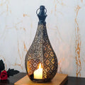 Moroccan-style black and gold teardrop candle lantern with intricate hollow metal filigree and a glowing candle.