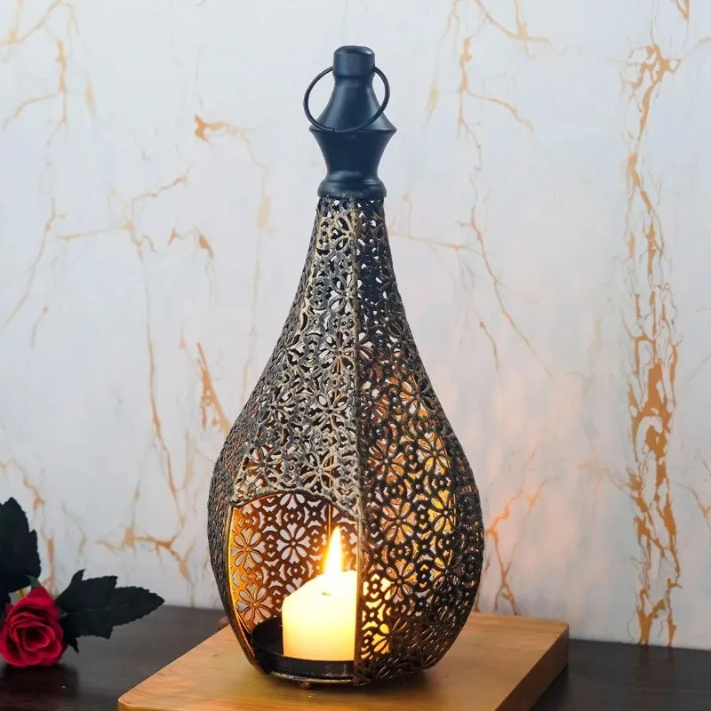 Moroccan-style black and gold teardrop candle lantern with intricate hollow metal filigree and a glowing candle.