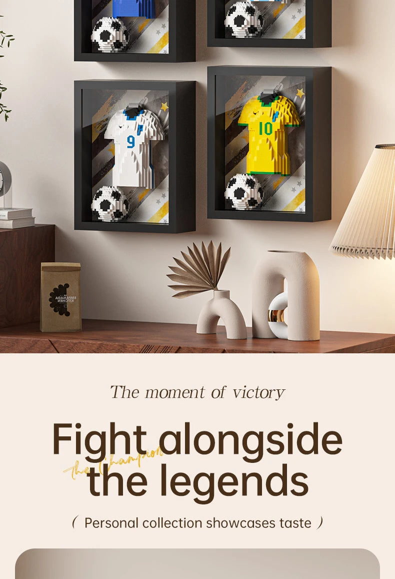 Wall-mounted black display frames featuring 3D brick-built football shirts and soccer balls on patterned backgrounds.