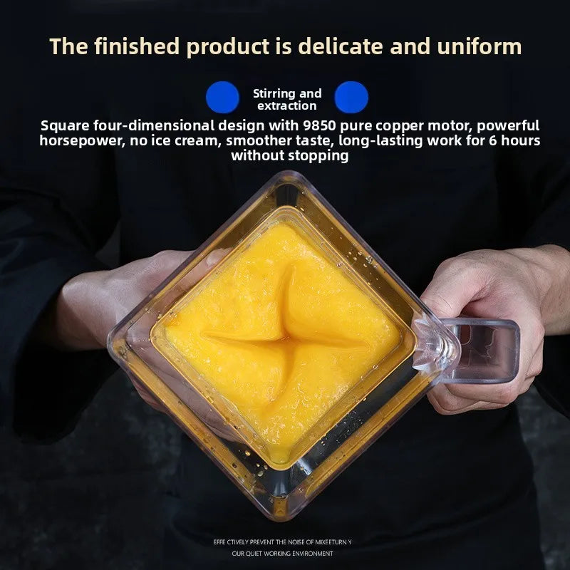 Square commercial blender jar filled with smooth yellow smoothie, held by a person in black.