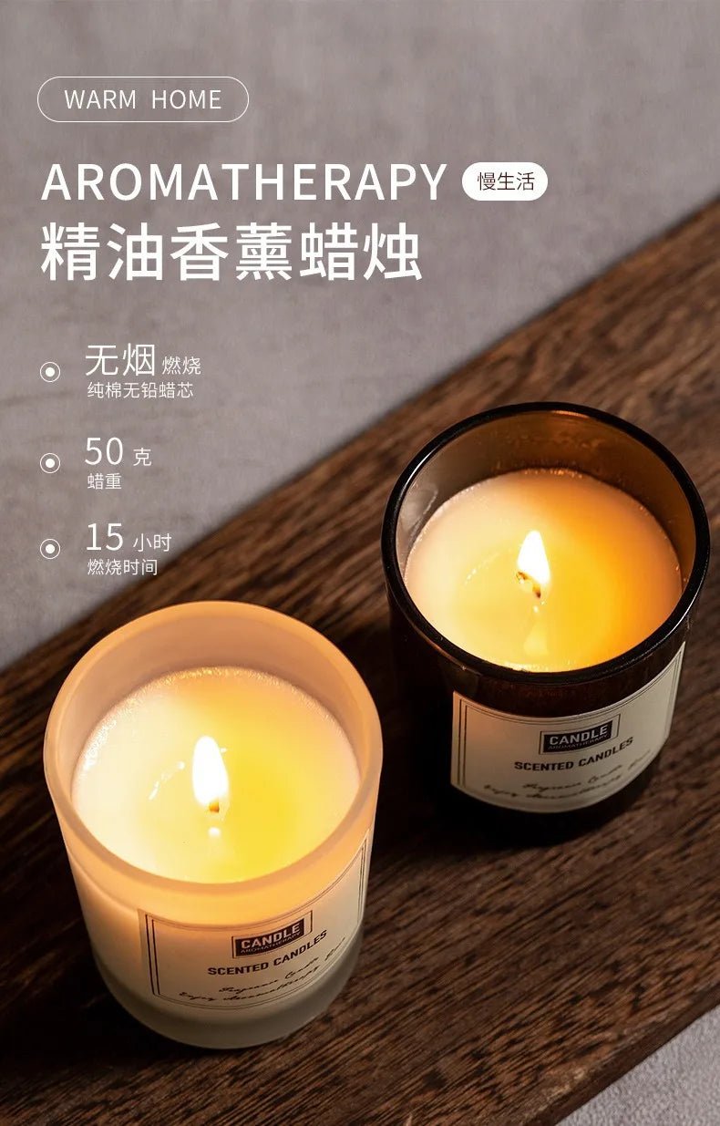 Two lit aromatherapy candles in frosted white and black glass jars on a wooden surface. 15-hour smoke-free burn time.