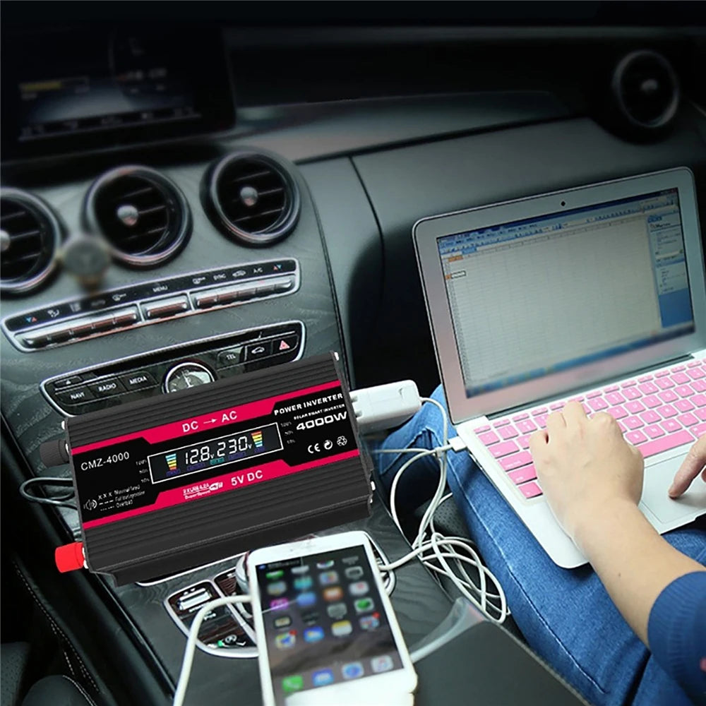 Black and red 4000W car power inverter with LCD display, shown connected to a laptop and smartphone in a car interior.