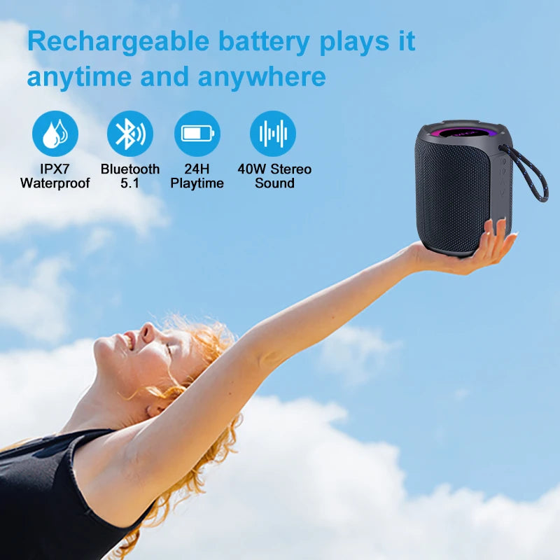 A person holds a compact, black waterproof Bluetooth speaker featuring 360-degree sound and a carry strap.