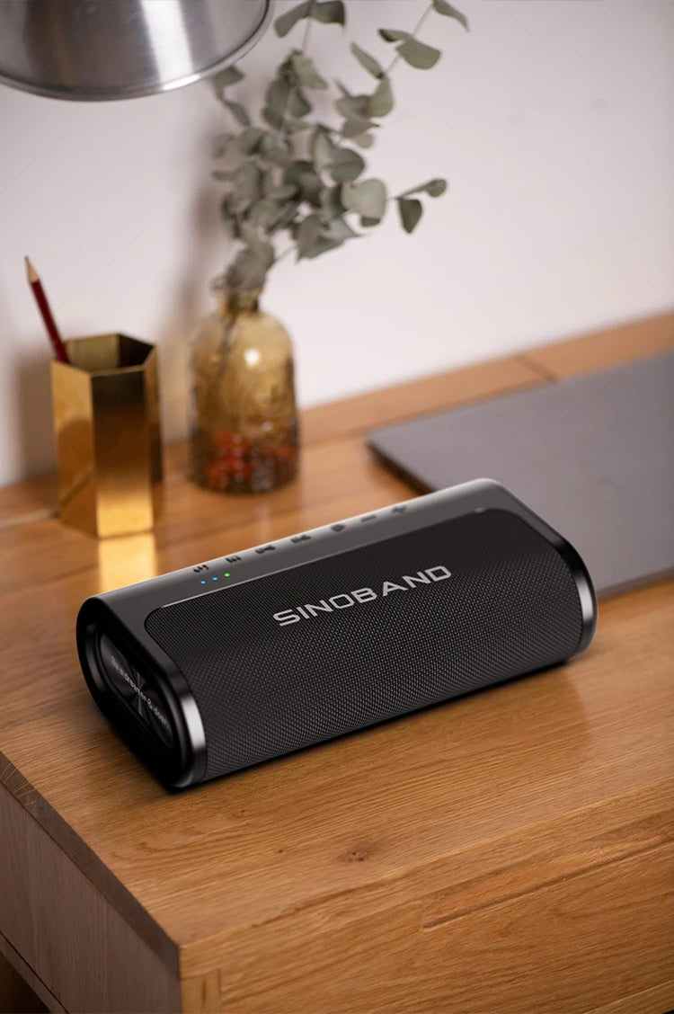 A sleek, black 80W wireless Bluetooth speaker with top-mounted control buttons, sitting on a wooden desk.