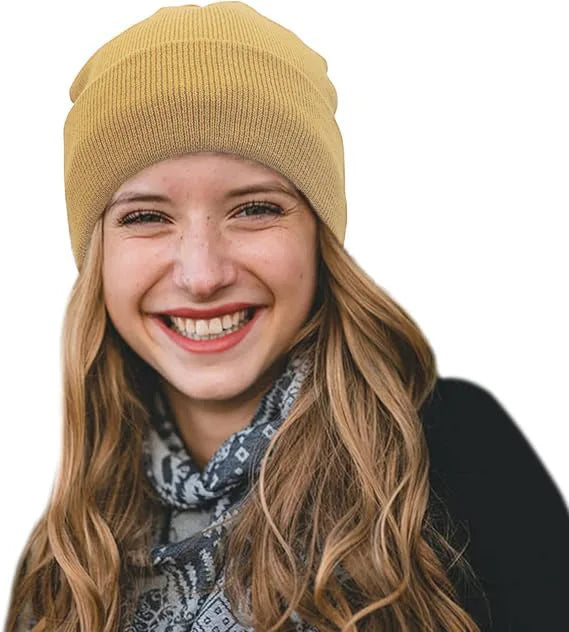 A woman wearing a mustard yellow knitted winter beanie, featuring a smooth satin lining for hair protection.