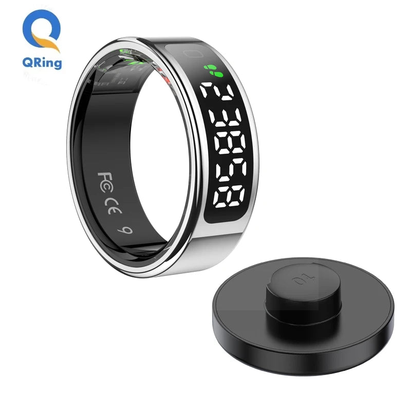 Silver smart fitness ring with a digital touch display showing steps and a circular black charging dock.