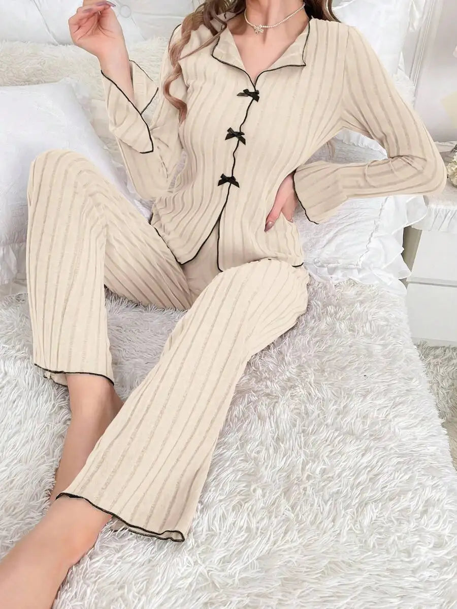 Beige ribbed lounge set with long sleeves, button-down front with small black bows, and flared trousers.