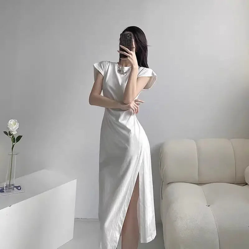 Elegant white midi dress with cap sleeves and a high side slit, showcasing a sleek, minimalist silhouette.