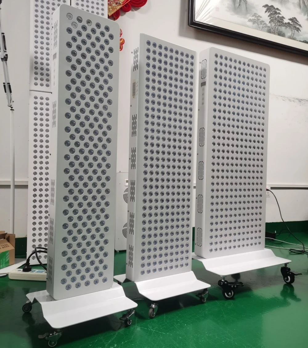 Three vertical white light therapy panels on wheeled stands in an indoor setting.