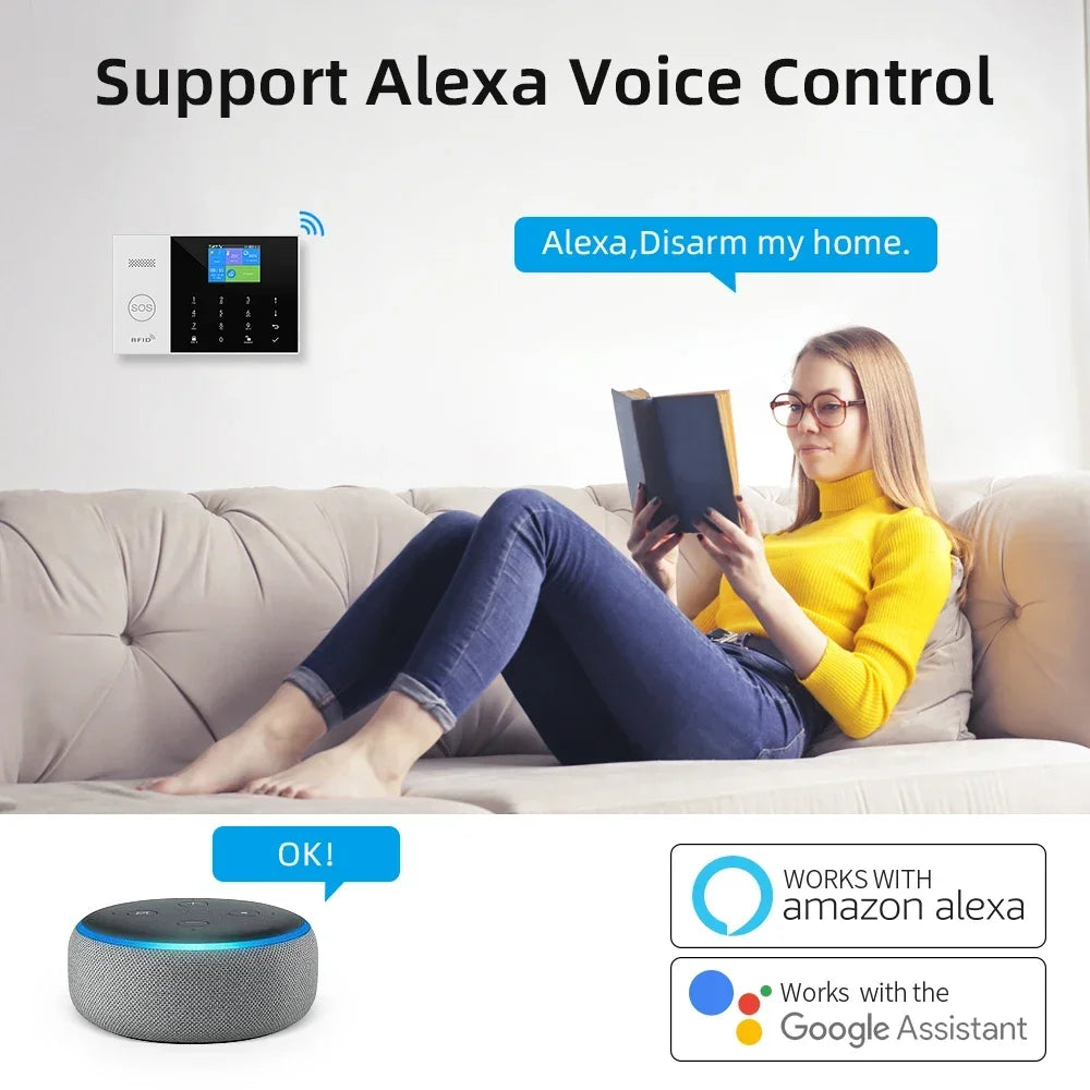 A white smart home alarm panel on a wall, controlled by voice via a smart speaker, as a woman reads on a sofa.