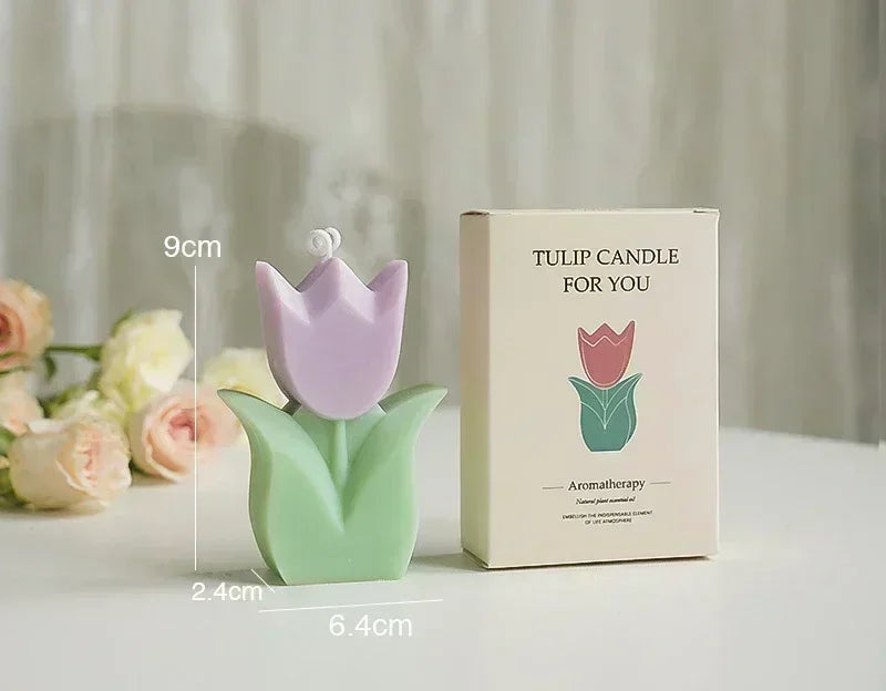 Pastel purple and green tulip-shaped aromatherapy candle next to its product box on a white surface.