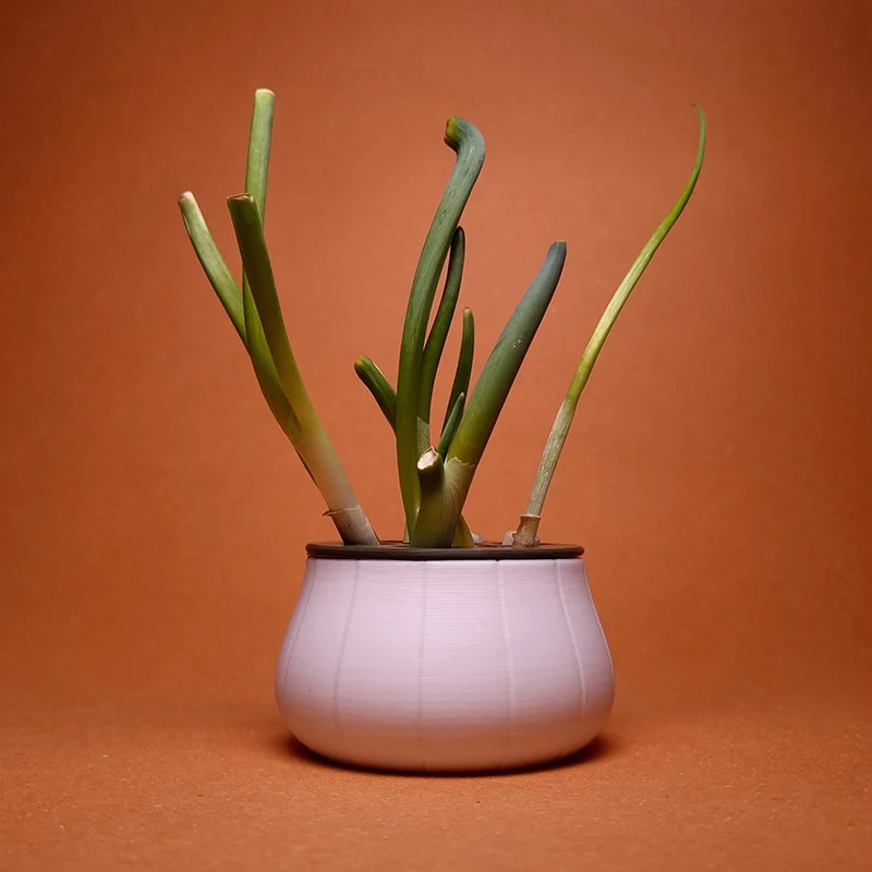 Green onions growing in a round, white 3D-printed hydroponic planter against a solid brown background.