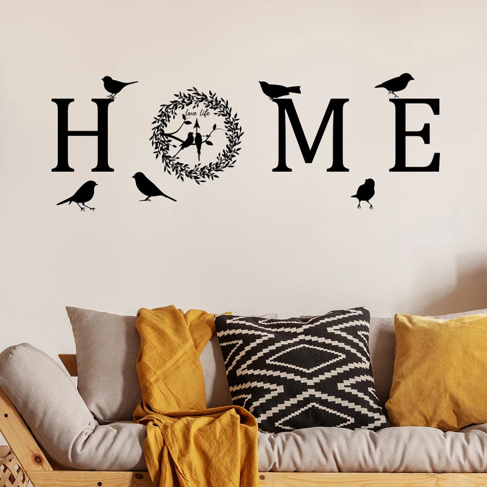 Black self-adhesive wall sticker featuring the word 'HOME' with a leaf wreath and bird silhouettes.