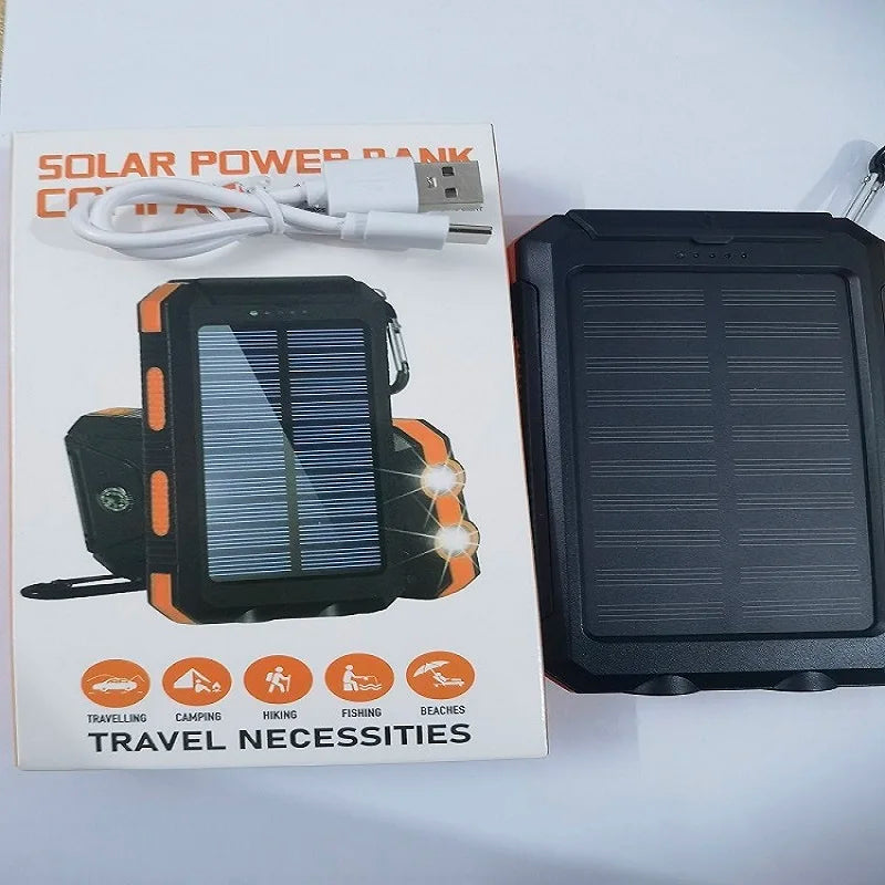 Black and orange solar power bank with built-in torch and compass, shown next to its packaging and charging cable.