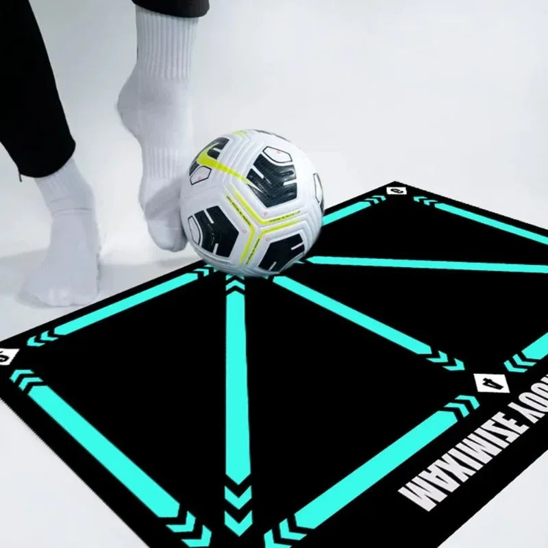 Person in white socks using a soccer ball on a black football training mat with bright turquoise directional lines.