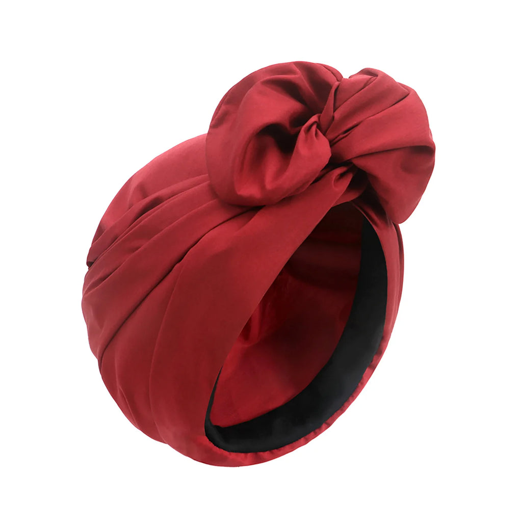 Deep red vintage-style turban hat featuring a decorative front knot and a smooth, satin-finish fabric.