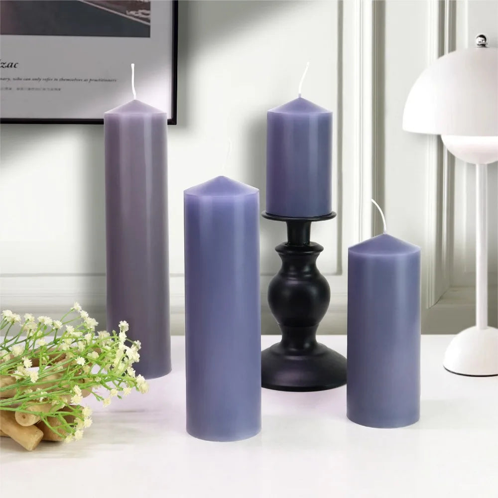 Four purple cylindrical pillar candles of varying heights with wicks, arranged on a white surface.