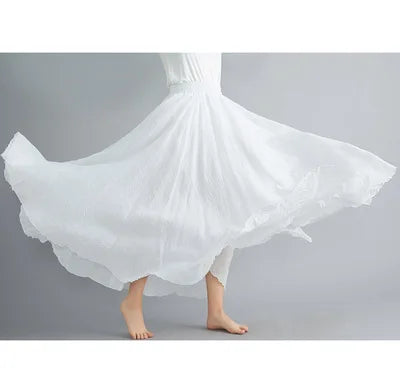 A person wearing a flowing, white maxi skirt with a flared, pleated design and a comfortable elasticated waist.