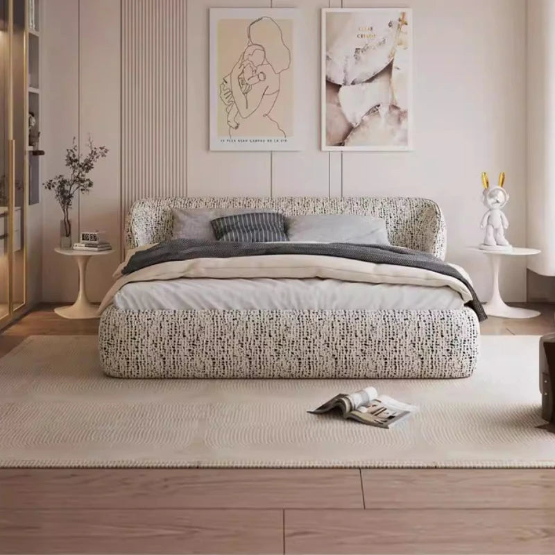 Modern low-profile bed frame in cream fabric with a black textured speckled pattern and a curved, cushioned headboard.